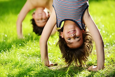 Niños en posición invertida jugando en el pasto.