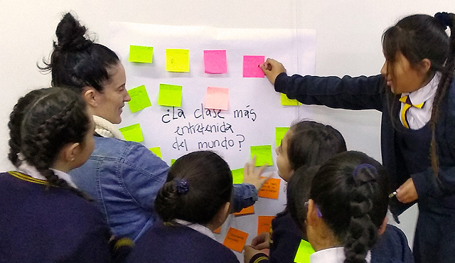 Fotografía de profesora y alumnas trabajando en equipo