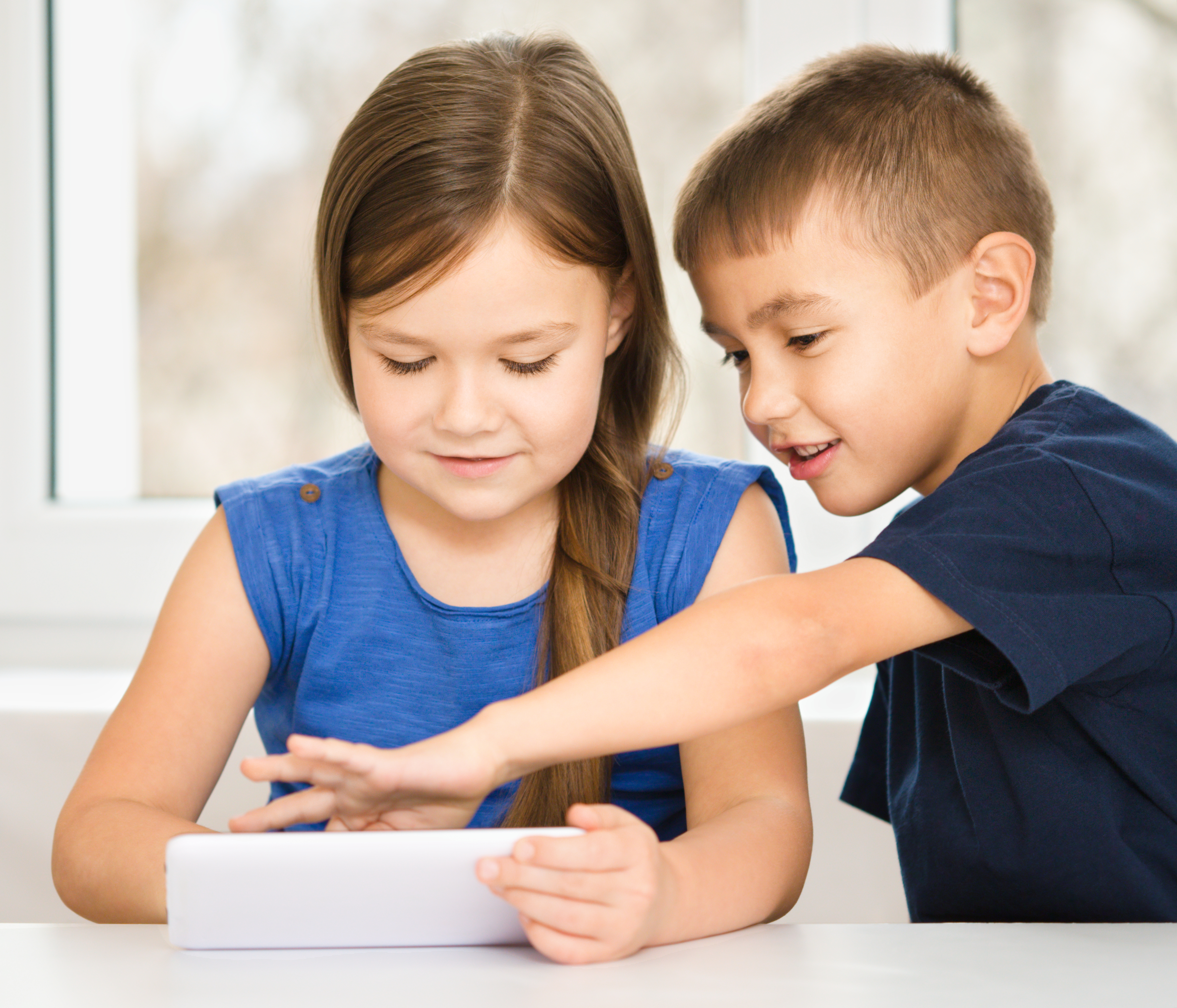 La imagen muestra a un niño y una niña observando algo en un dispositivo