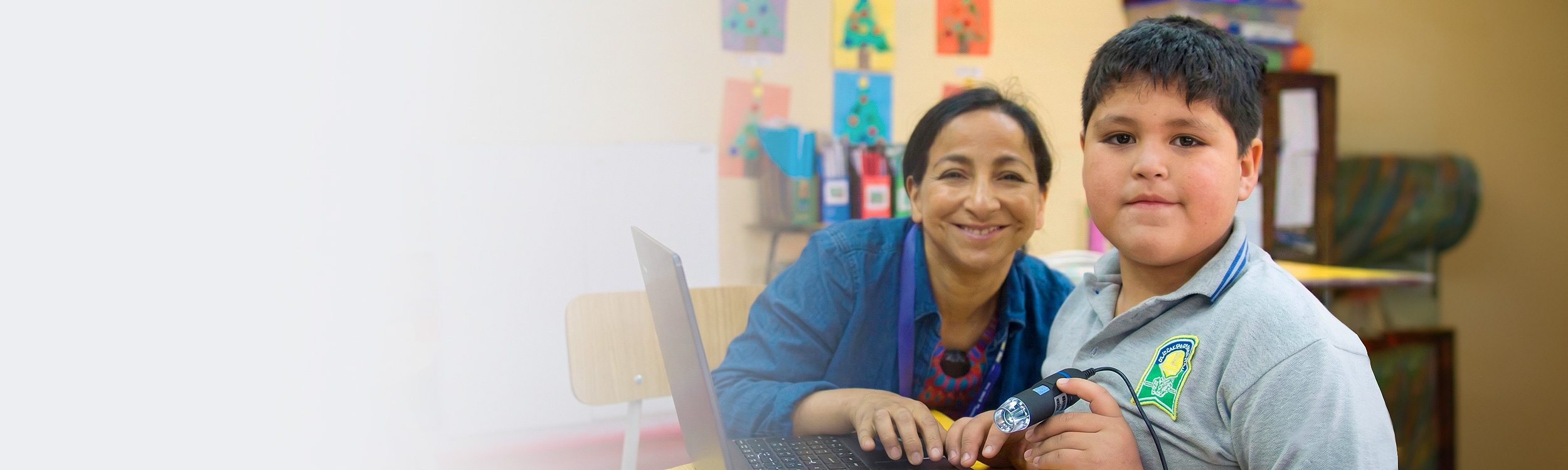 Fotografía de profesora estudiante varón mirando sonrientes hacia la cámara.