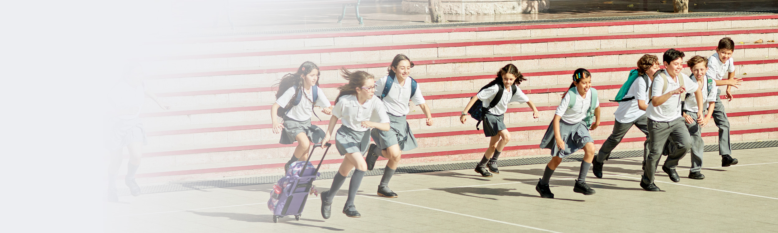 Ninos y niñas vestidos con uniforme escolar corriendo hacia la misma dirección.