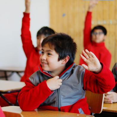niño en aula saludando feliz