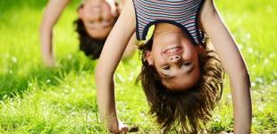 Niños en posición invertida jugando en el pasto. 