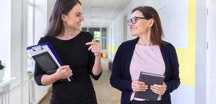 Docentes conversando en pasillo de una escuela