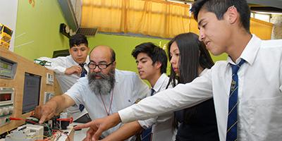 Profesor enseñando a sus estudiantes a armar un circuito en un Liceo Técnico Profesional.