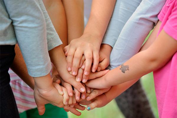 Manos entrelazadas de niños y niñas.