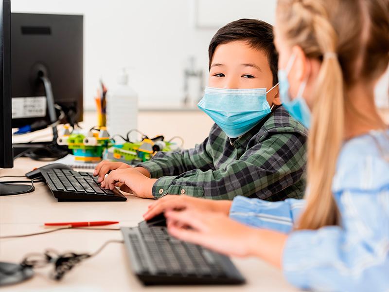Dos niños en clases frente a un teclado de computador