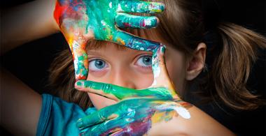 La imagen muestra una niña con las manos pintadas