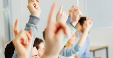 La imagen muestra a jóvenes levantando la mano