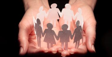 la imagen muestra dos manos juntas con unos recortes con figuras de personas