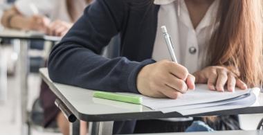 La imagen muestra a una estudiante escribiendo 
