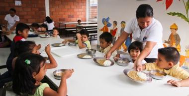La imagen muestra a niños y niñas recibiendo su alimentación