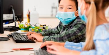 Dos niños en clase frente a un computador 