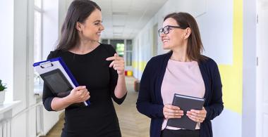 Docentes conversando en pasillo de una escuela